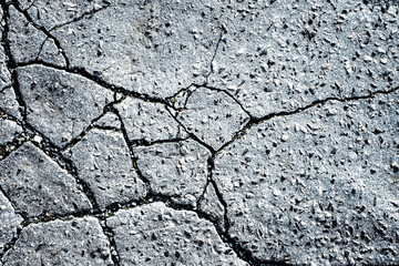 Texture of cracked asphalt with uneven surface and rough edges