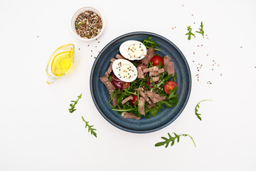 A fresh salad with tender beef, nutritious eggs, and fresh greens aragula, olive oil, seeds perfect for healthy meals anytime.