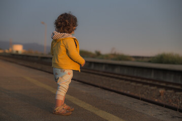 Danger of trains running over people, Child at train station, Train tracks, Child standing in front of safety line with yellow bump texture line on a  passenger platform at an empty train station.