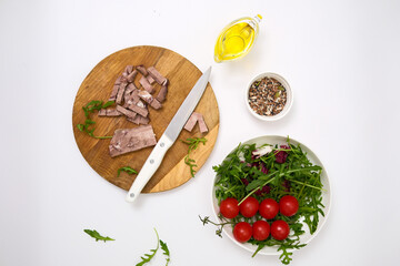 A fresh salad with tender beef, nutritious eggs, and fresh greens aragula, olive oil, seeds perfect for healthy meals anytime. Cutting ingredients on cutboard.