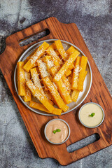 Porção de polenta frita com parmesão ralado servida sobre tábua de madeira