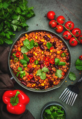 Chili con carne with minced beef, beans, paprika, corn, cilantro, jalapeno pepper in tomato sauce, tex-mex cuisine in green frying pan, top view