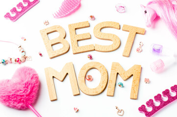 BEST MOM Wooden Letters with Pink Accessories. Heart-shaped fluffy pen, candy-shaped containers with pink beads, nail polish bottles, a separator for pedicures, and jewelry items for girls.