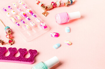 Pink accessories. Colored false nails, nail polish bottles, a separator for pedicures, and jewelry items for girls.