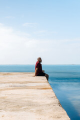 Man Sitting on a Pier with Ocean Horizon: Serene Coastal Scene