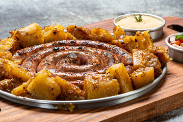 Porção de linguiça, servida com mandioca frita, farofa, vinagrete, cebolas, maionese e molho...