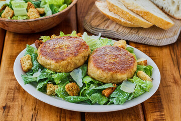 crispy crab cakes on a ceasar salad served with sliced bread