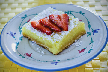 lemon bars topped with powdered sugar and fresh strawberries