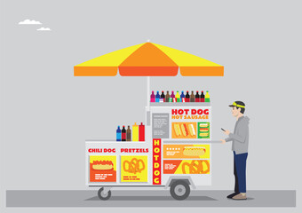 a hotdog stall with yellow and red color with umbrella and moving wheels selling sodas hotdog chilli dog and pretzels run by young man