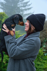 Young woman holding her dachshund dog, smiling in a foggy day