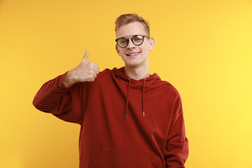 Happy man showing thumbs up on yellow background. Like gesture