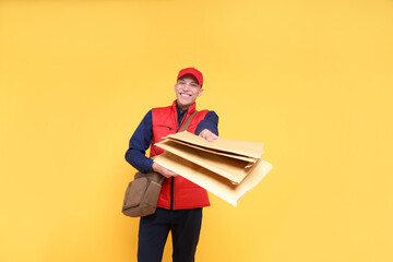 Happy postman with bag giving envelopes on yellow background