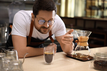 Barista sniffing aromatic filter coffee at table in cafe