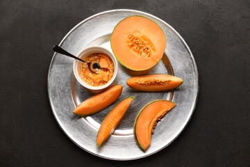 Plate with ripe cut melon on black background
