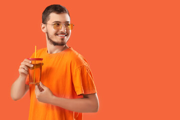 Fototapeta premium Young man with glass of juice on red background