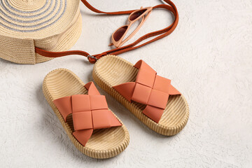 Female stylish flip flops with beach accessories on light background
