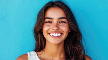 Fototapeta premium Close up of a beautiful young woman smiling with healthy white teeth on a blue background