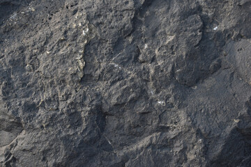 Close-up of a rough and textured rock surface. Raw stone surface showing organic shapes and lines. Earthy rock texture ideal for backgrounds or designs.