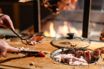A person is cutting meat on a wooden cutting board