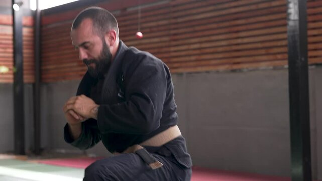 Martial artist practicing ukemi breakfalls during training in a gym
