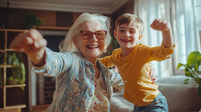Beautiful grandmother and grandson together at home dancing and having fun - Cheerful grandma and nephew spending quality time together.