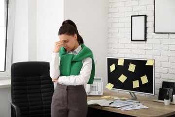 Young woman suffering from headache near workplace in office