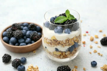 Glass of tasty granola with yogurt on light background, closeup