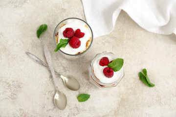 Glass and jar of tasty granola with yogurt on light background