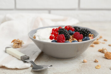 Bowl of tasty granola with yogurt and different berries on grunge background, closeup