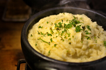 Mashed potatoes in a clay pot. Rustic cooking scene. Vintage wood background, rustic style.