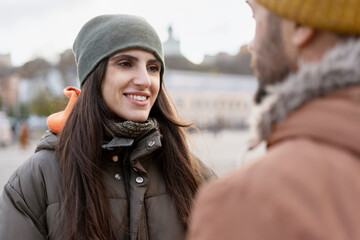 Young woman smiling and talking to her boyfriend in a city square during winter