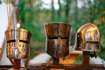 Three metal helmets are displayed on a wooden stand