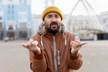 Confused man gesturing with hands in urban setting