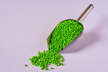 Green masterbatch granules in stainless steel scoop isolated on white background,color pigment...