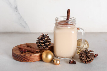 Mason jar of tasty eggnog cocktail with cinnamon, star anise, pine cones and Christmas balls on white background