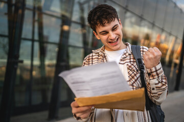 Young adult man student open and read files from envelope outdoor