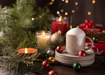 Festive Holiday Scene with Cozy Mug of Creamy Hot Chocolate Surrounded by Candles, Christmas Ornaments, and Pine Branches for a Warm Winter Celebration Atmosphere