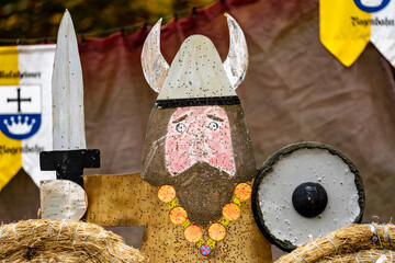 A man with a Viking helmet and a sword is standing in front of a banner