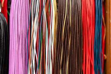 A row of colorful cords are hanging on a shelf