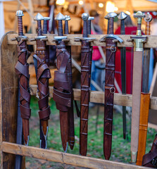 A row of swords are hanging on a wooden rack