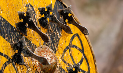 A yellow shield with a black cross on it and five black axes on it