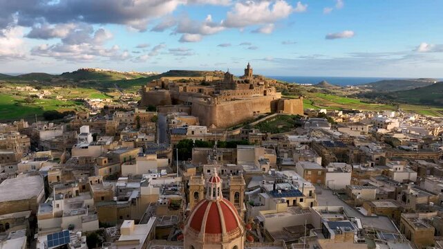 4k Aerial view of Historic fort, Citadel Ruins on cliff overlooking valley at sunset with lush greenery in the background. island Gozo. Malta