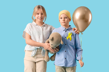 Little children with gold ribbon, toy and balloon on blue background. Childhood cancer awareness