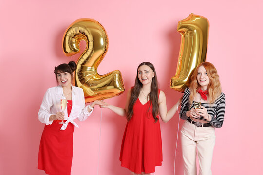 Coming of age party - 21st birthday. Group of young women celebrating with number shaped balloons on pink background