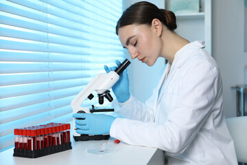 Laboratory testing. Doctor working with microscope at table indoors