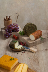 Cheeses in different spices on the table among fruits and greens