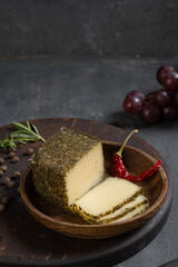 Cheeses in different spices on the table among fruits and greens