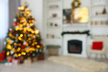 Blurred view of beautifully decorated Christmas tree near fireplace in room. Festive interior design