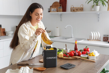 Young woman throwing banana peel into container for compost in kitchen