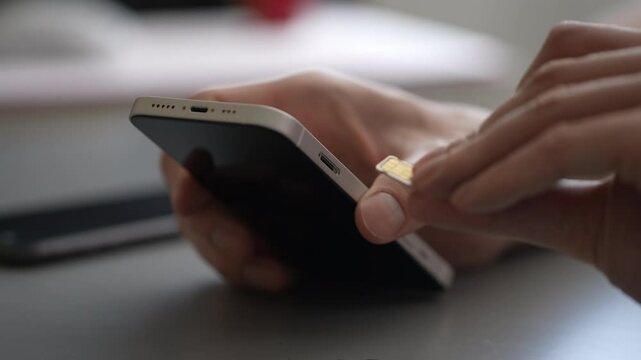 Close-up of male hands inserting, removing and replacing sim card from mobile phone, demonstrating process of changing cellular provider or managing mobile data. Shooting in slow motion.